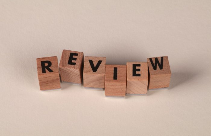Wooden blocks with letters forming the word 'Review' on a soft pastel background.