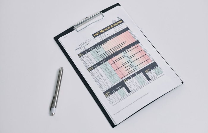 A hair mineral analysis form on a clipboard with a silver pen on a white background.