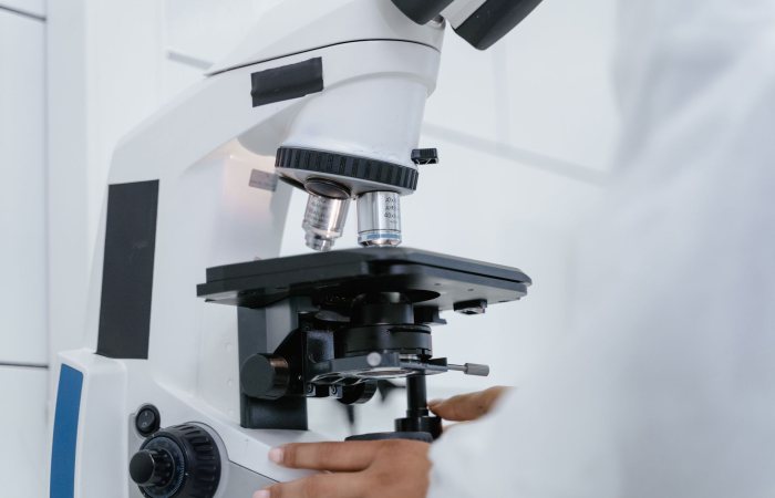 Detailed view of a scientist operating a microscope in a laboratory setting.