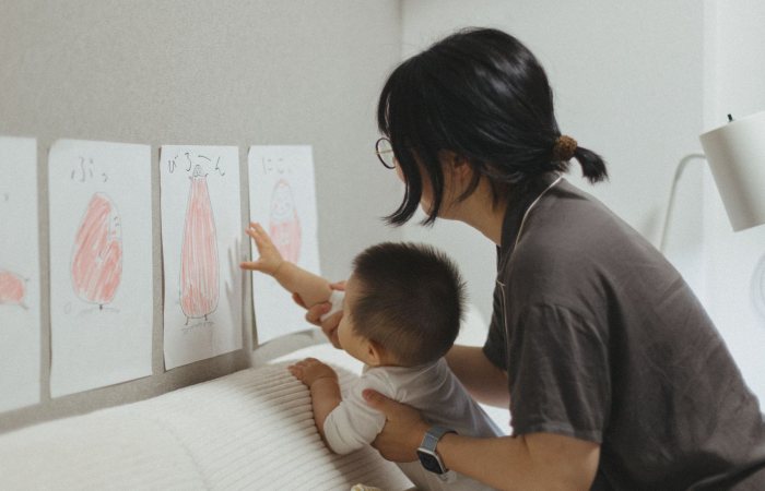 A mother and child engage in a learning activity, exploring art drawings in a cozy indoor setting.