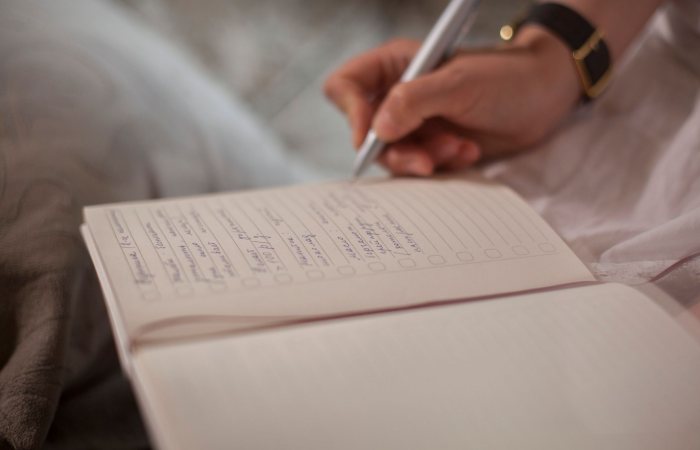 A close-up image of a person's hand writing in a notebook, emphasizing focus and creativity.