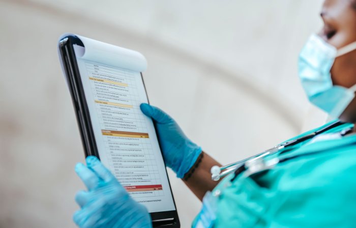 Side view of crop African American female medic in uniform reading text on paper at work
